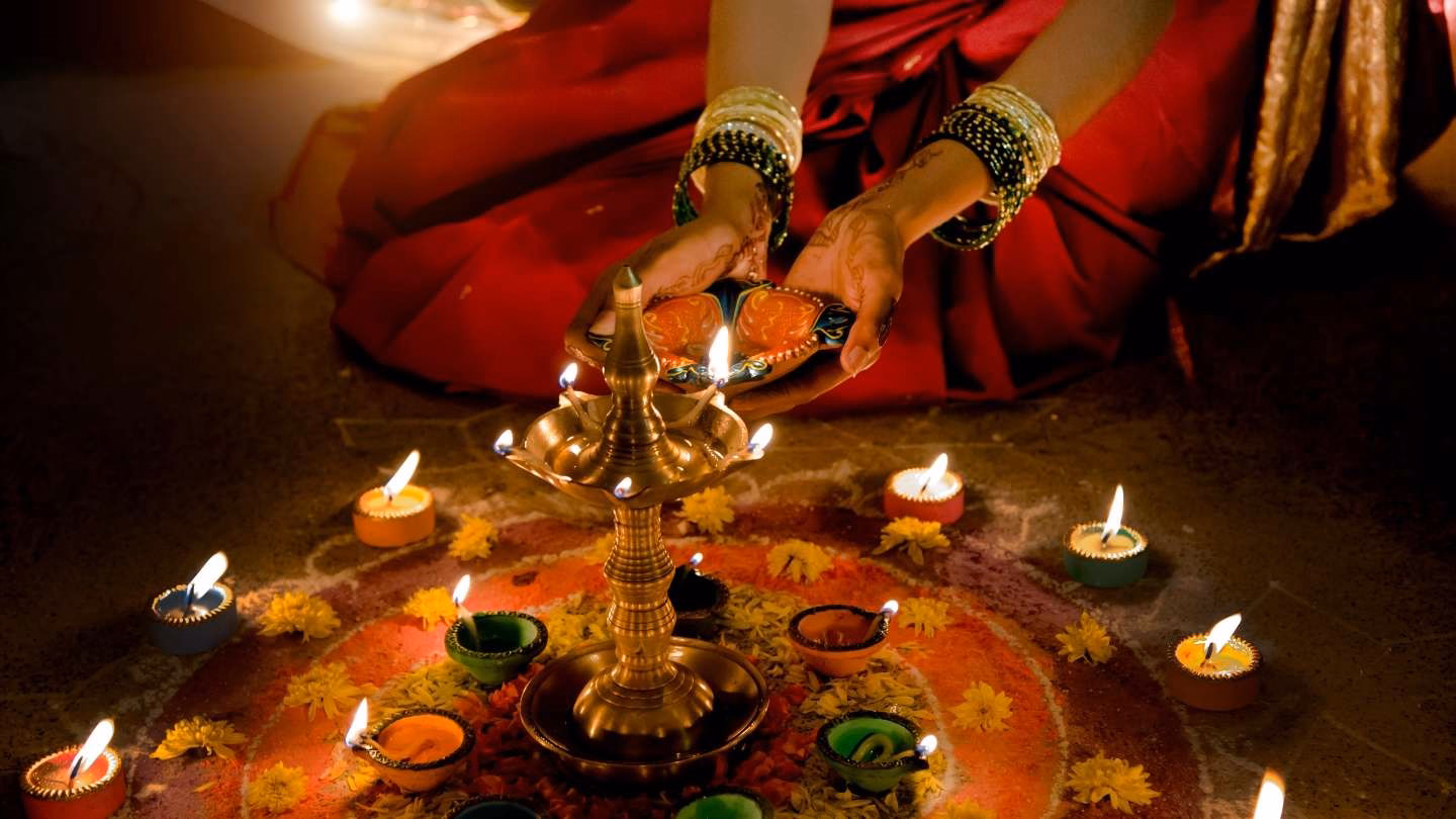 Woman performing Diwali rituals with lit candles.
